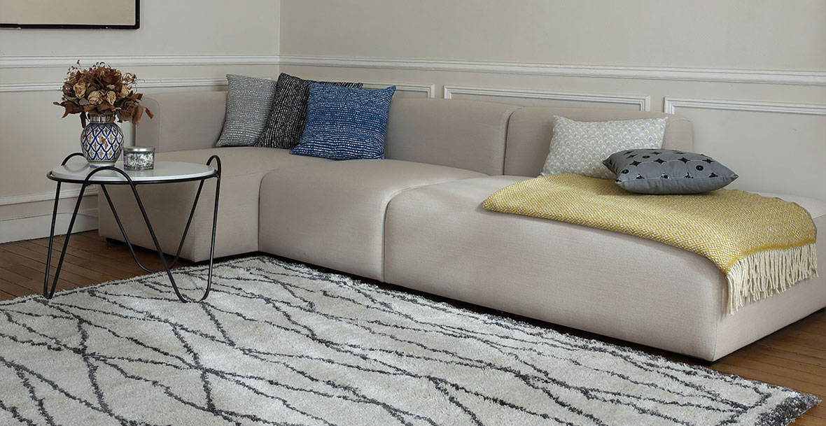 Ein Sofa auf einem Teppich in einem Wohnzimmer dekoriert mit Kissen.