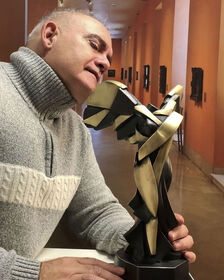 Miguel Guía observe de très près sa sculpture moderne représentant la Victoire de Samothrace.