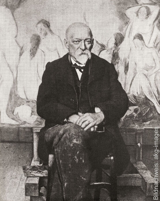 Historisk sort-hvid-fotografi af den franske maler Paul Cézanne, der sidder i sit atelier foran et stort maleri med nøgenfigurer.