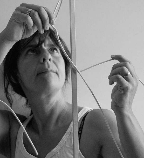 La sculptrice belge Ann Vrielinck lève les yeux vers le ciel tandis qu'elle travaille avec concentration sur une sculpture.