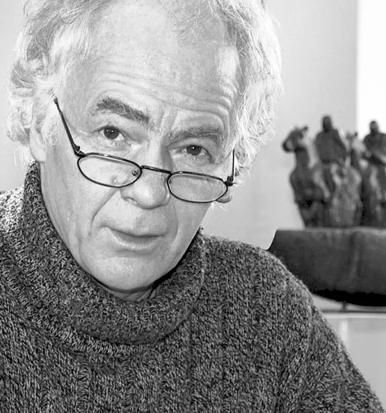 Et sort-hvidt portræt af den tyske kunstner og billedhugger Christoph Fischer med briller og rullekravebluse foran en hesteskulptur i baggrunden.