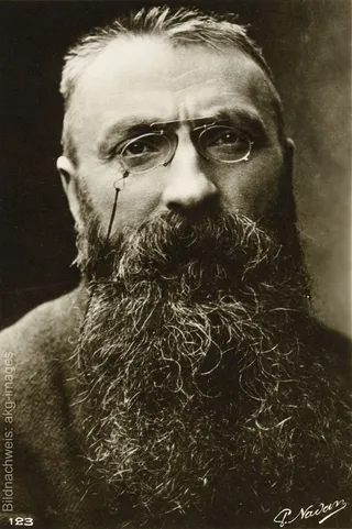 Historisches Porträt des französischen Bildhauers Auguste Rodin mit Brille und langem Bart.