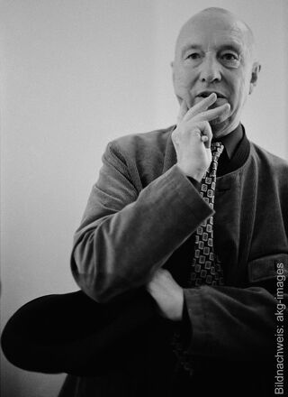 Schwarz-Weiß-Porträt des Künstlers Georg Baselitz mit einer nachdenklichen Geste, die Hand am Kinn und eine gemusterte Krawatte tragend.