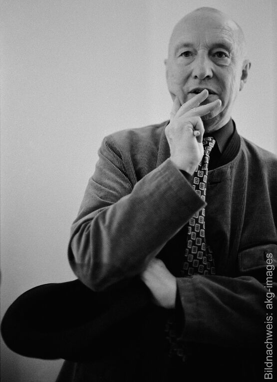 Retrato en blanco y negro del artista Georg Baselitz con un gesto pensativo, la mano en la barbilla y una corbata estampada.