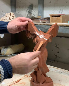 Dans l'atelier, des mains façonnent les contours d'une sculpture en argile à l'aide d'un pinceau à modeler.
