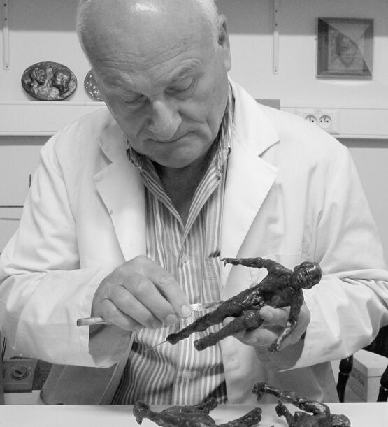 L'artista e scultore belga Jacques Vanroose sta lavorando con grande concentrazione a una piccola statuetta in bronzo.
