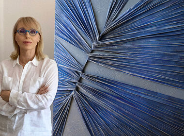 Alla Grande se tient devant une grande œuvre d'art structurée, de couleur bleue.
