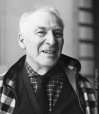 Et sort-hvidt portræt af den smilende maler Marc Chagall iført en mønstret jakke, skjorte og slips.