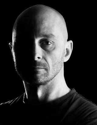 Schwarz-Weiß-Porträt des Fotografen Olivier Lacour, dessen Gesicht zur Hälfte im tiefen Schatten liegt.
