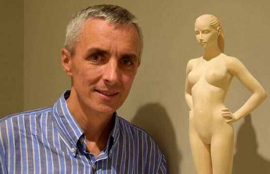 El escultor del Tirol del Sur Richard Senoner posa sonriente junto a una de sus delicadas esculturas de madera.