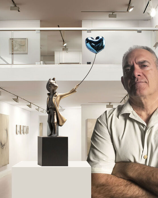Le sculpteur Miguel Guía se tient à côté de sa sculpture en bronze représentant un garçon tenant un ballon en forme de cœur.