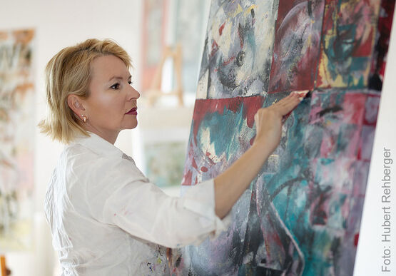The painter Sabine Türk is working intently on a large-scale, vibrantly coloured painting.