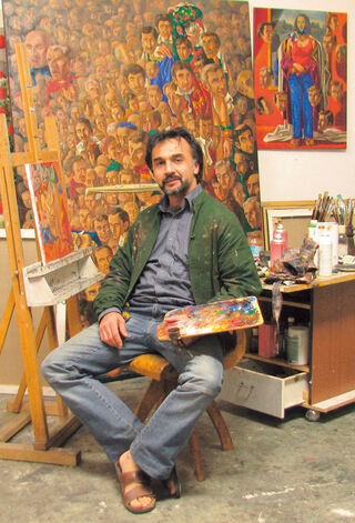 The artist and painter Kaikaoss, seated with a mixing palette in his studio in front of his large-scale, richly detailed figure paintings.