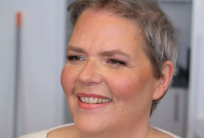 Primo piano dell’artista tedesca Ute Bivona, sorridente, con i capelli corti e grigi.