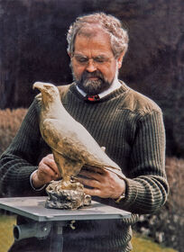 Bildhauer Kurt Arentz nimmt im Freien letzte Anpassungen an einer detailreichen Adler-Skulptur aus Bronze vor.