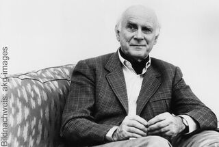 Ritratto storico di Loriot in giacca, seduto su un divano a motivi geometrici.