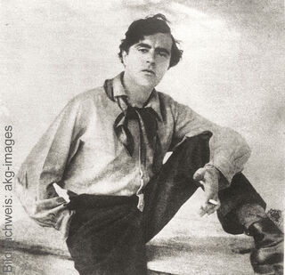 Photographie historique en noir et blanc du peintre Amedeo Modigliani, la cravate lâche et une cigarette à la main.