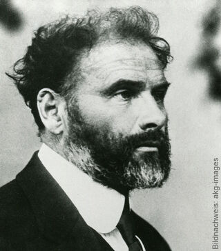 Photographie historique en noir et blanc de l'artiste et peintre autrichien Gustav Klimt, vu de profil, arborant une barbe fournie et vêtu d'un costume sombre à col blanc.